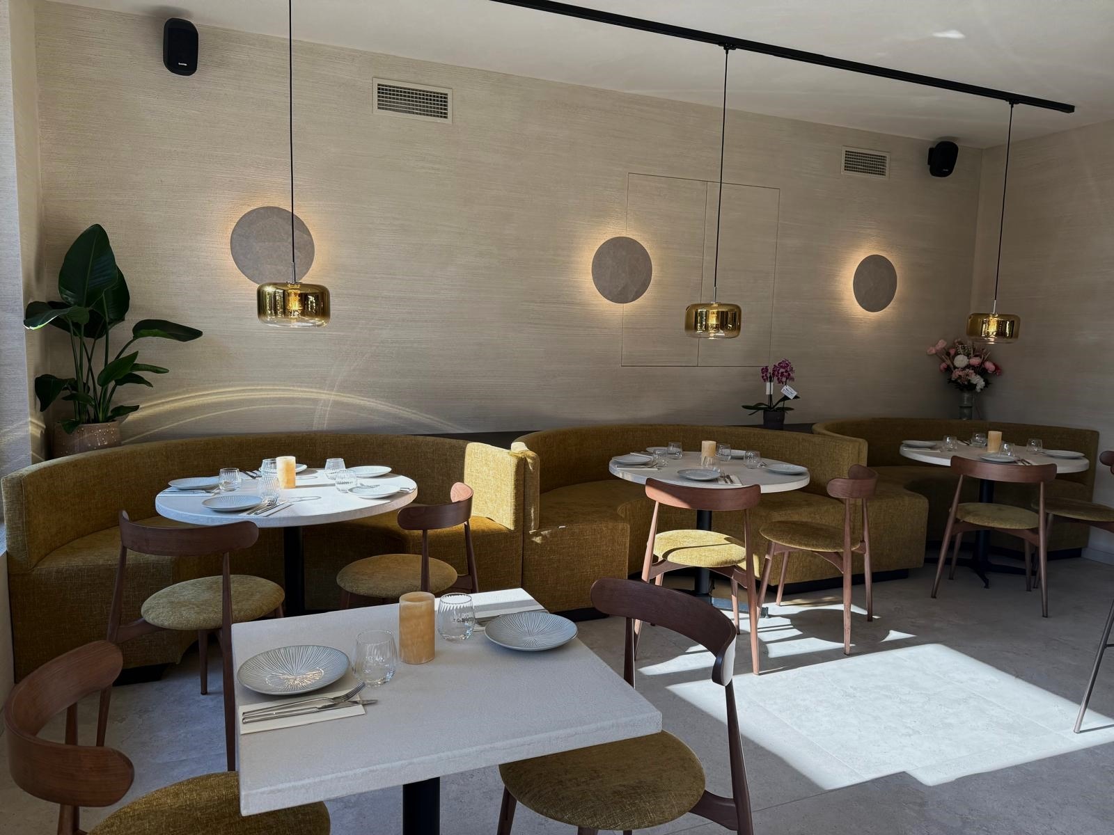 Volledige overzichtsopname van het restaurantgedeelte in Bistrobar Triple, met een speelse mix van ronde tafels horeca, maatwerk zitbanken in warme mosterdtint, en elegante houten horeca stoelen met gestoffeerde zit. De verlichting en ronde wandaccenten versterken het stijlvolle karakter van deze doordachte horeca interieur inrichting.