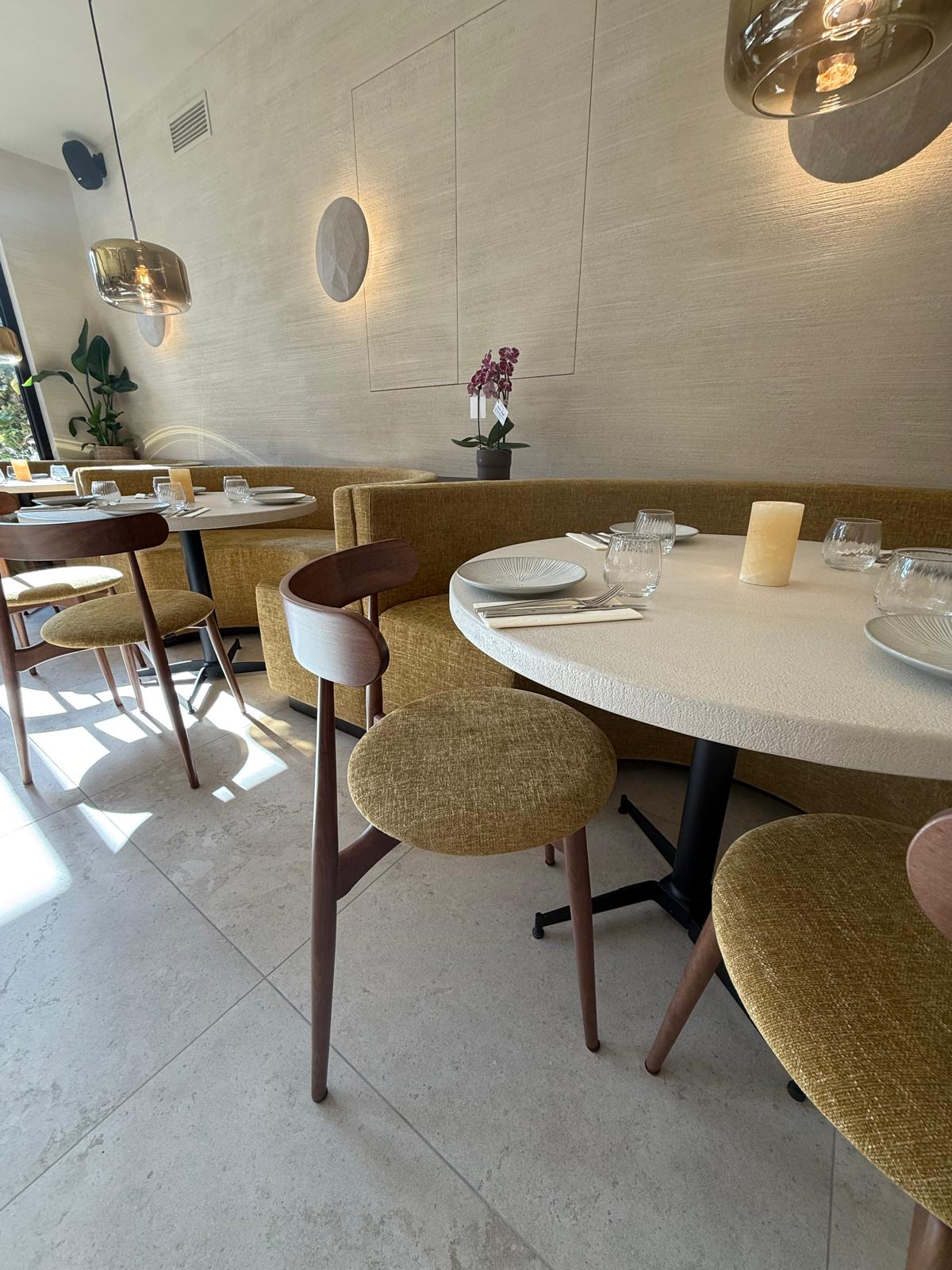 Zonnige setting in Bistrobar Triple met een lange, op maat gemaakte horeca wandbank in mosterdgeel, perfect afgestemd op de houten Fieke-stoelen met beklede zitting. Deze stijlvolle combinatie van vormen en texturen tilt de inrichting restaurant naar een hoger niveau.