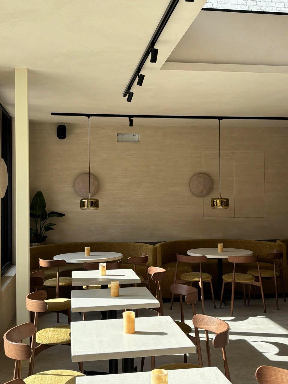 Lichtovergoten interieur van Bistrobar Triple met meerdere opstellingen van tafels en stoelen horeca, waarbij de Fieke-stoelen in beukhout en gestoffeerde zitting perfect passen bij de strakke, op maat gemaakte rechte banken. Deze horeca meubels combineren functionaliteit met stijl in een eigentijds kader.