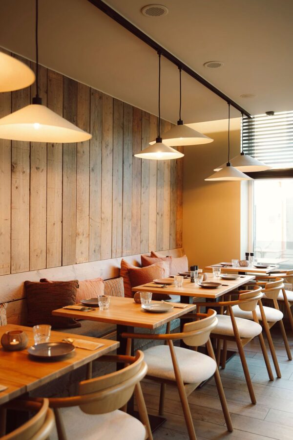 Gezellige hoekopstelling met armstoelen horeca type Green, uitgevoerd in eik met houten rugleuning en beklede zitting van Búni. De horeca tafels hebben zwarte onderstellen in epoxy met massief eiken blad, perfect voor een warme en comfortabele inrichting restaurant.