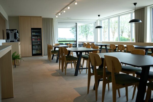 Houten stoelen met groene bekleding gecombineerd met een zwarte tafel in een professionele interieurinrichting.