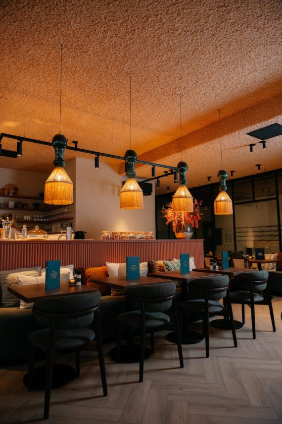 Detail van ronde houten tafel met gestoffeerde stoelen op een visgraatvloer.